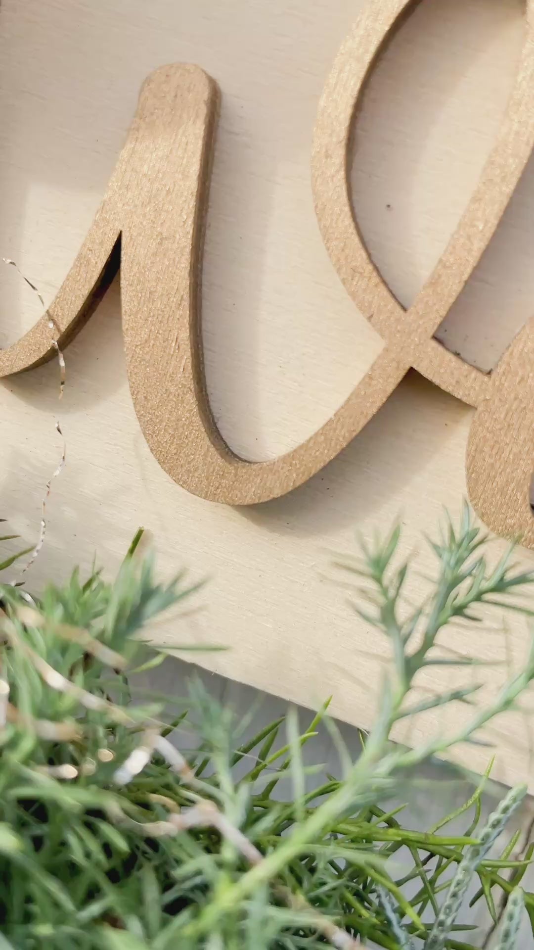 Video zeigt den Holzloop ‚Frohe Weihnachten‘ mit filigranem Holzschriftzug, dekoriert mit Zypresse, Thuja, Tannengrün, Kugeln in Gold- und Cremetönen, Birkensternen und Lerchenzapfen. Perspektiven inklusive Tür-, Wand- und Detailansicht.