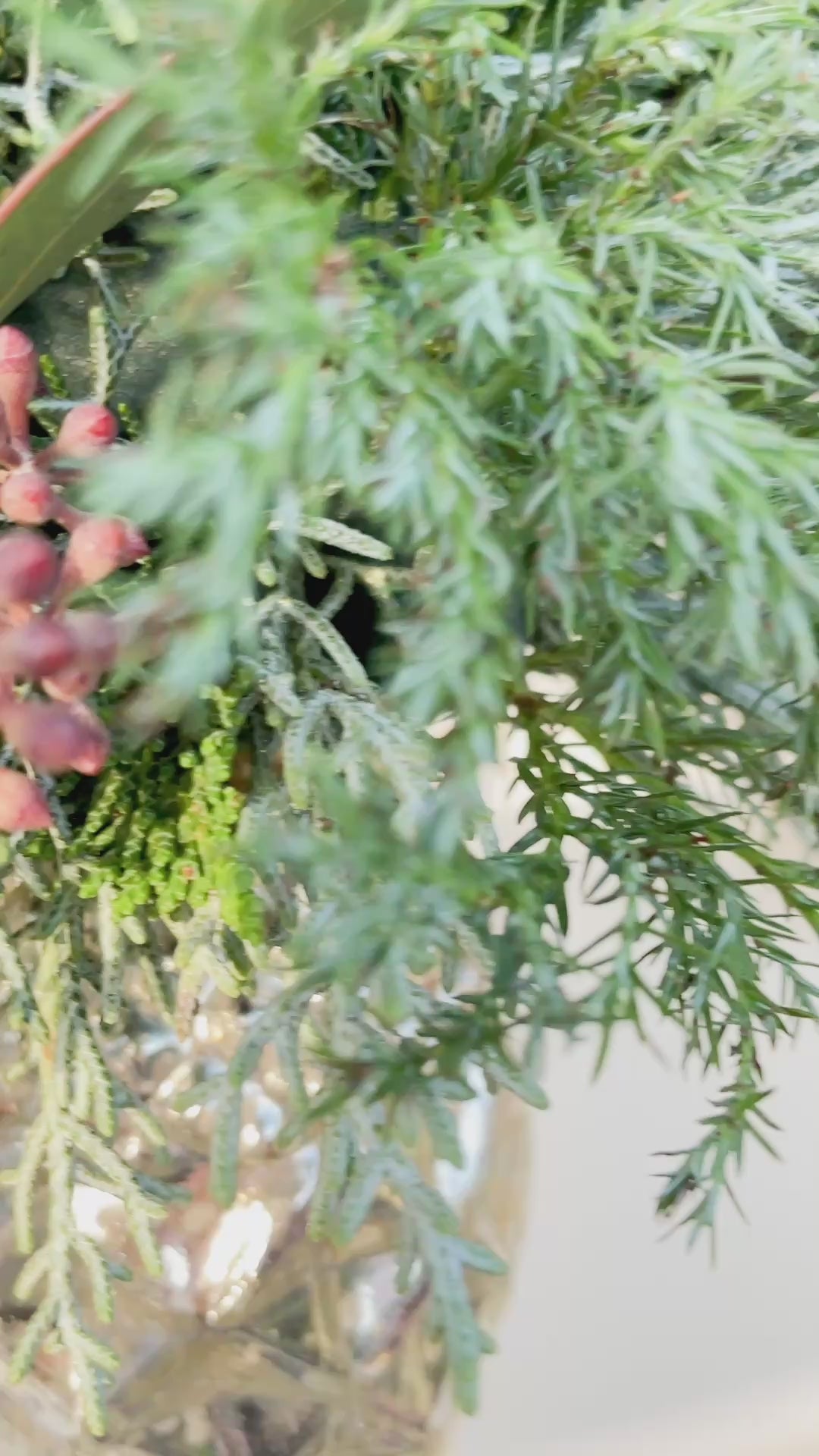 Video zeigt den Glaszapfen ‚Winter Elegance‘: Silber, Höhe ca. 10 cm, dekoriert mit Mini-Bouquet aus Nadel- und Koniferengrün, Eukalyptus und weißem Schleierkraut. Perspektiven inklusive Nahaufnahmen und Aufhängung an Fenster oder Wand.